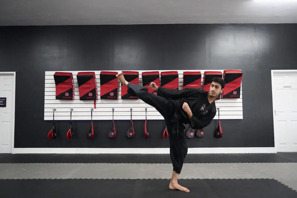 Adult martial arts participants kicking pads during stress-relief workout session
